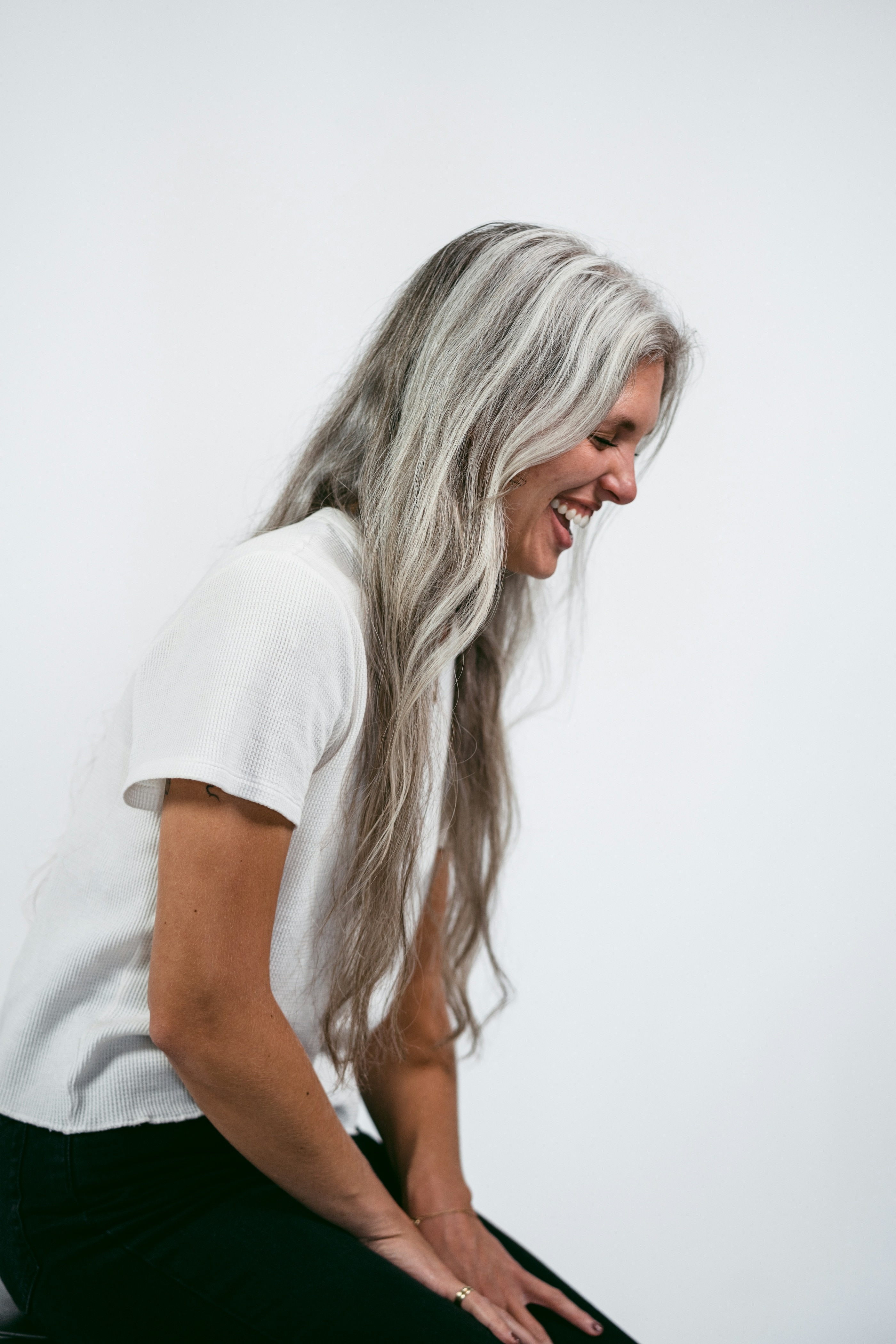 Woman with long grey hair smiling while seated
