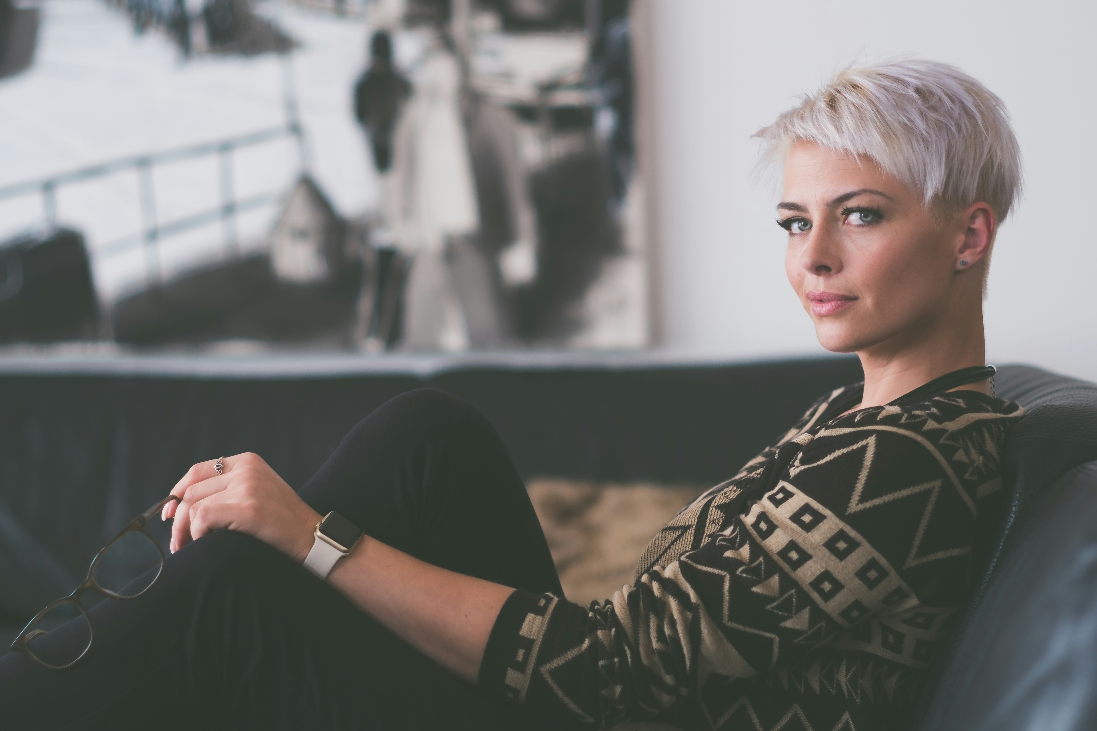 Woman with short silver hair sitting on a dark sofa