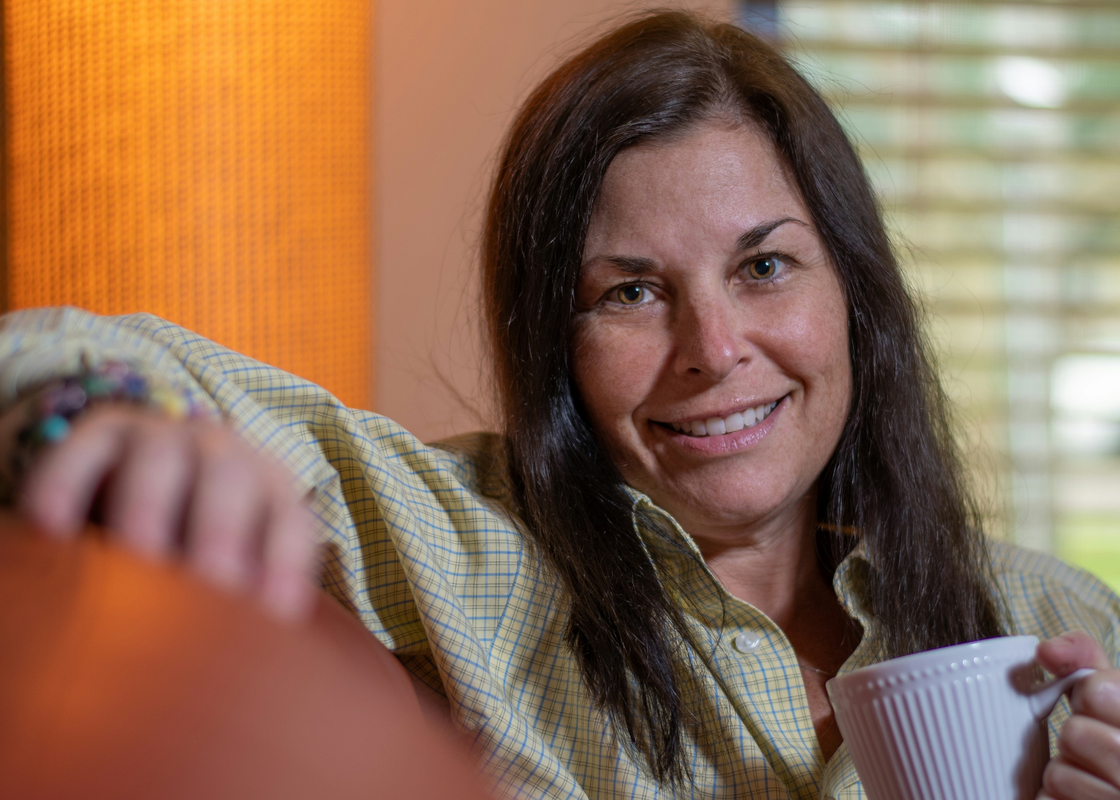 Woman smiling on a sofa while holding a mug